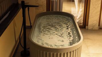 A spa area with a hot tub, a glass door, and a marble wall.