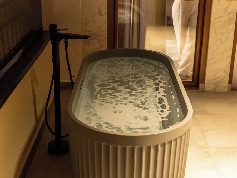 A spa area with a hot tub, a glass door, and a marble wall.
