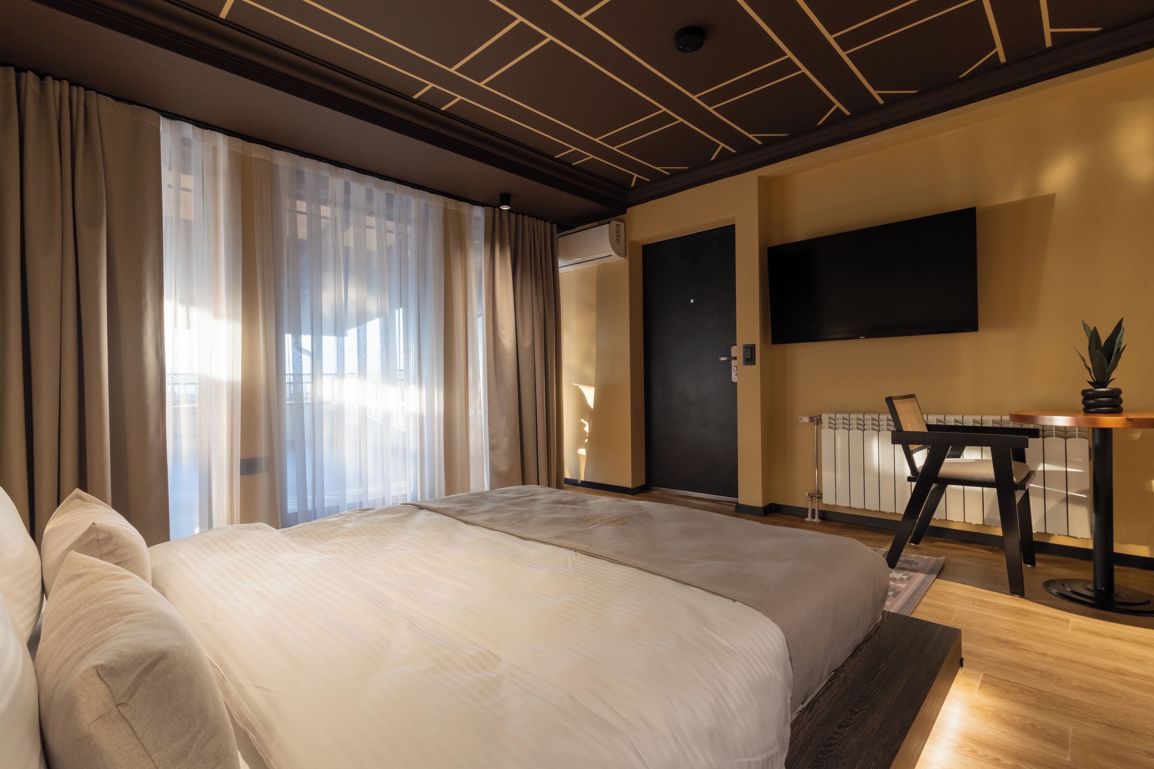 A modern hotel room with a large bed, a desk, and a television.