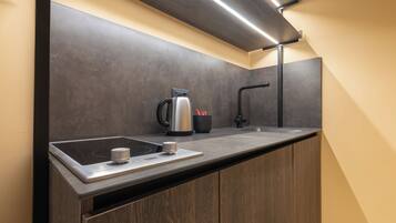 A modern kitchen with a built-in induction cooktop, a kettle, and a coffee maker.