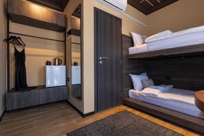 Una habitación compacta con una cama nido, un armario, un espejo y un pequeño rincón americano.
