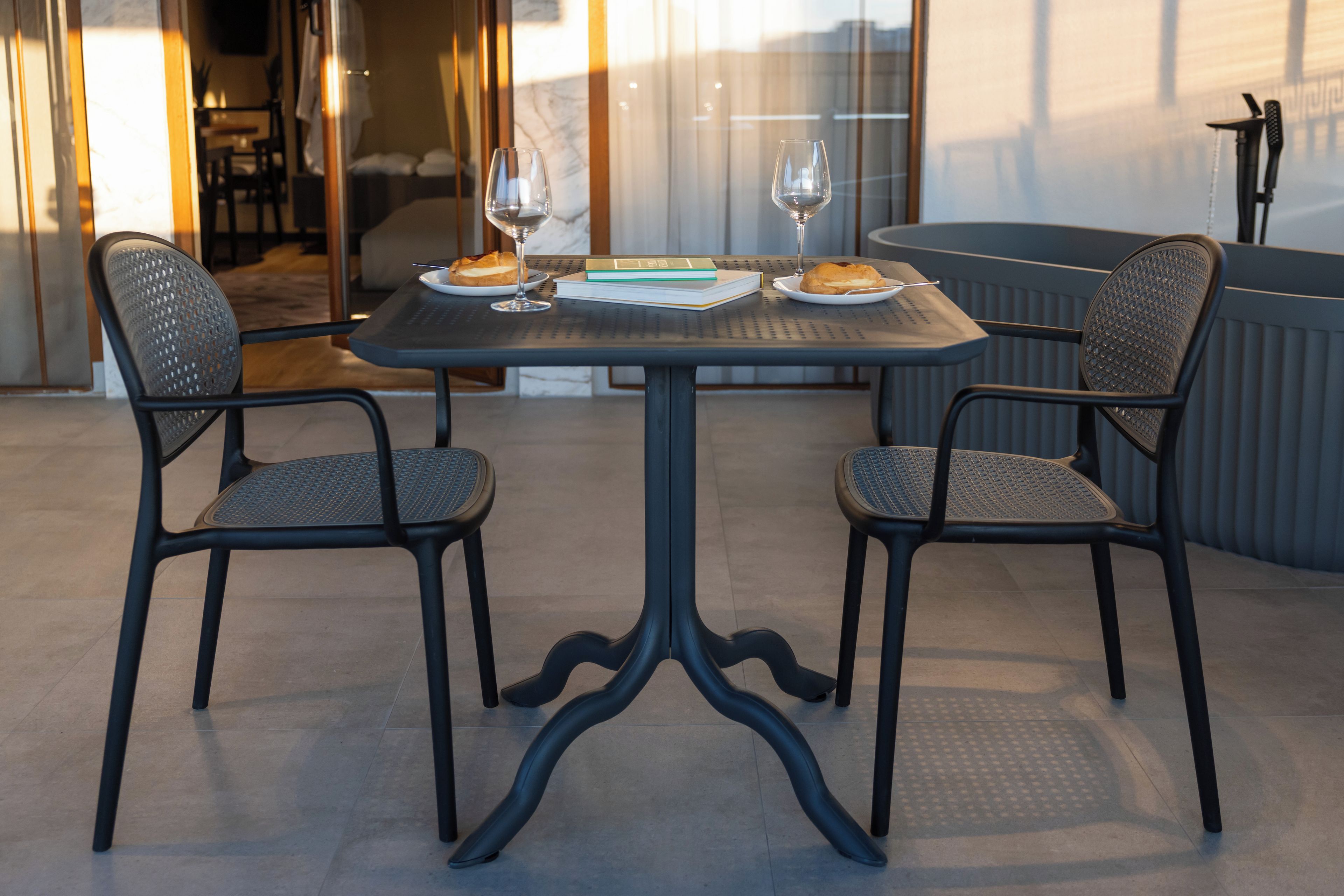 A dining table with two chairs, a wine glass, and a plate with food.