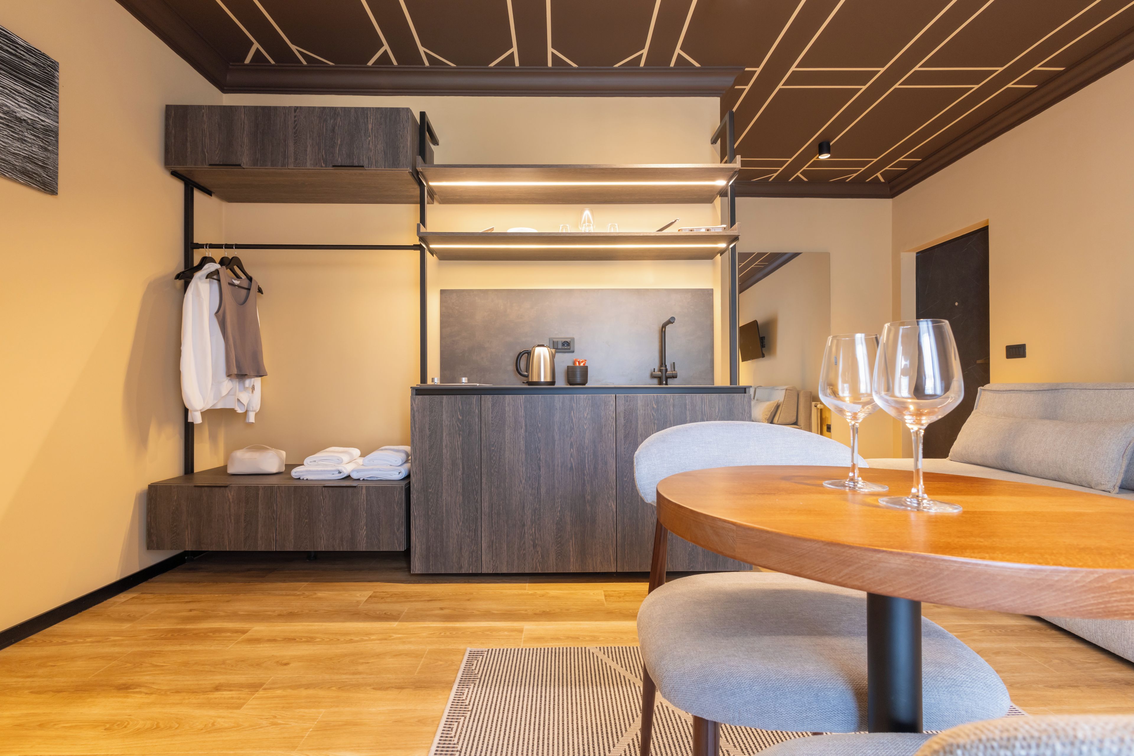 Habitación de hotel compacta con kitchenette, zona de comedor con mesa y sillas, y rincón de descanso con sofá.