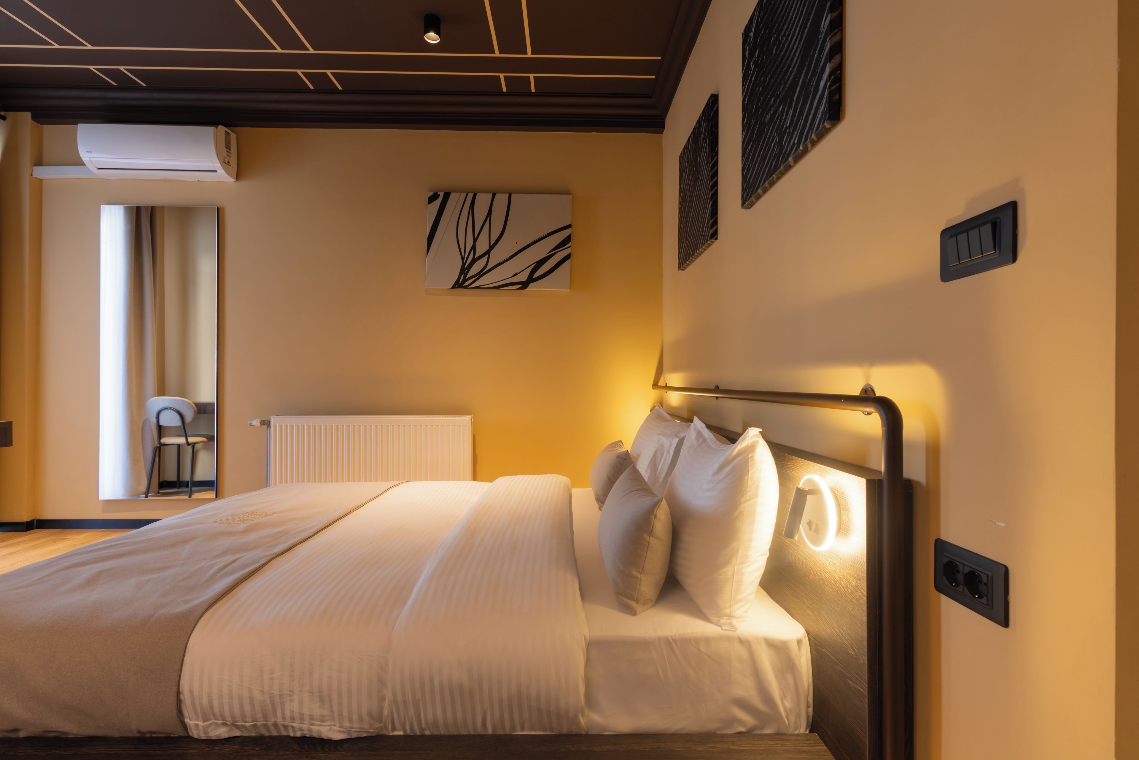 Ein modernes Schlafzimmer mit einem Bett, einem Heizkörper, einer Wand-Klimaanlage und einem Fenster mit Vorhängen.