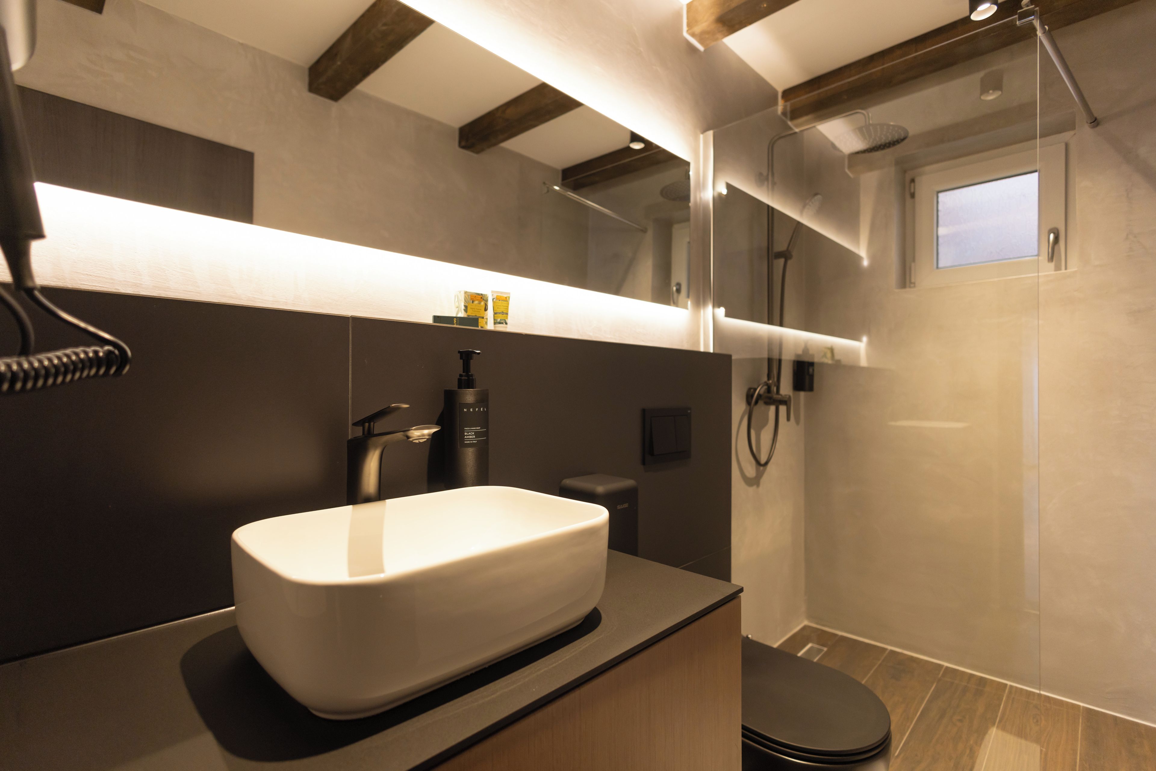 Une salle de bain moderne avec un grand lavabo blanc, une douchette à main et des toilettes.
