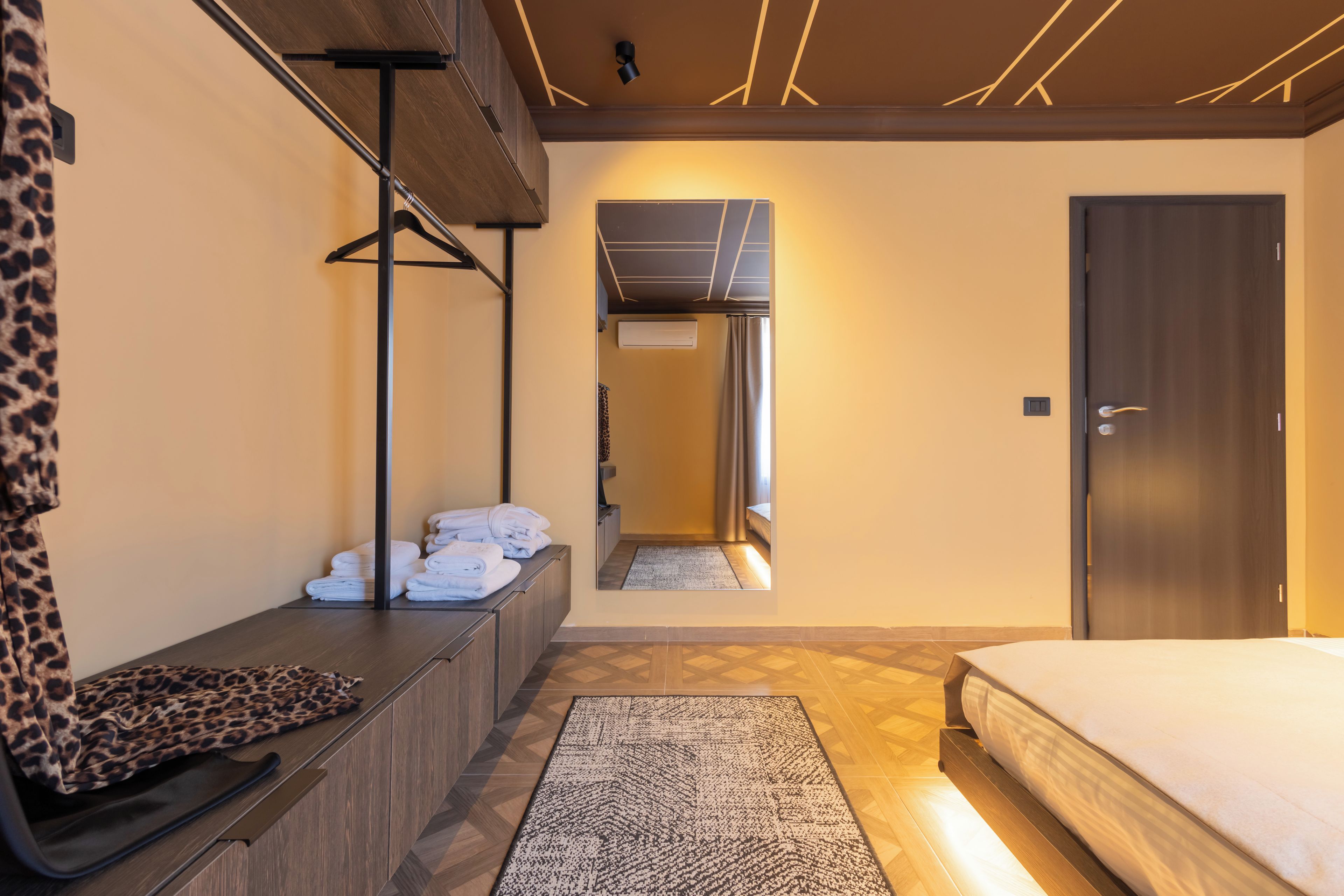 Habitació d'hotel moderna amb un llit, una zona de seients amb tovalloles, una mànega per abrics i vista al passadís.