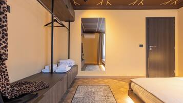 Habitació d'hotel moderna amb un llit, una zona de seients amb tovalloles, una mànega per abrics i vista al passadís.