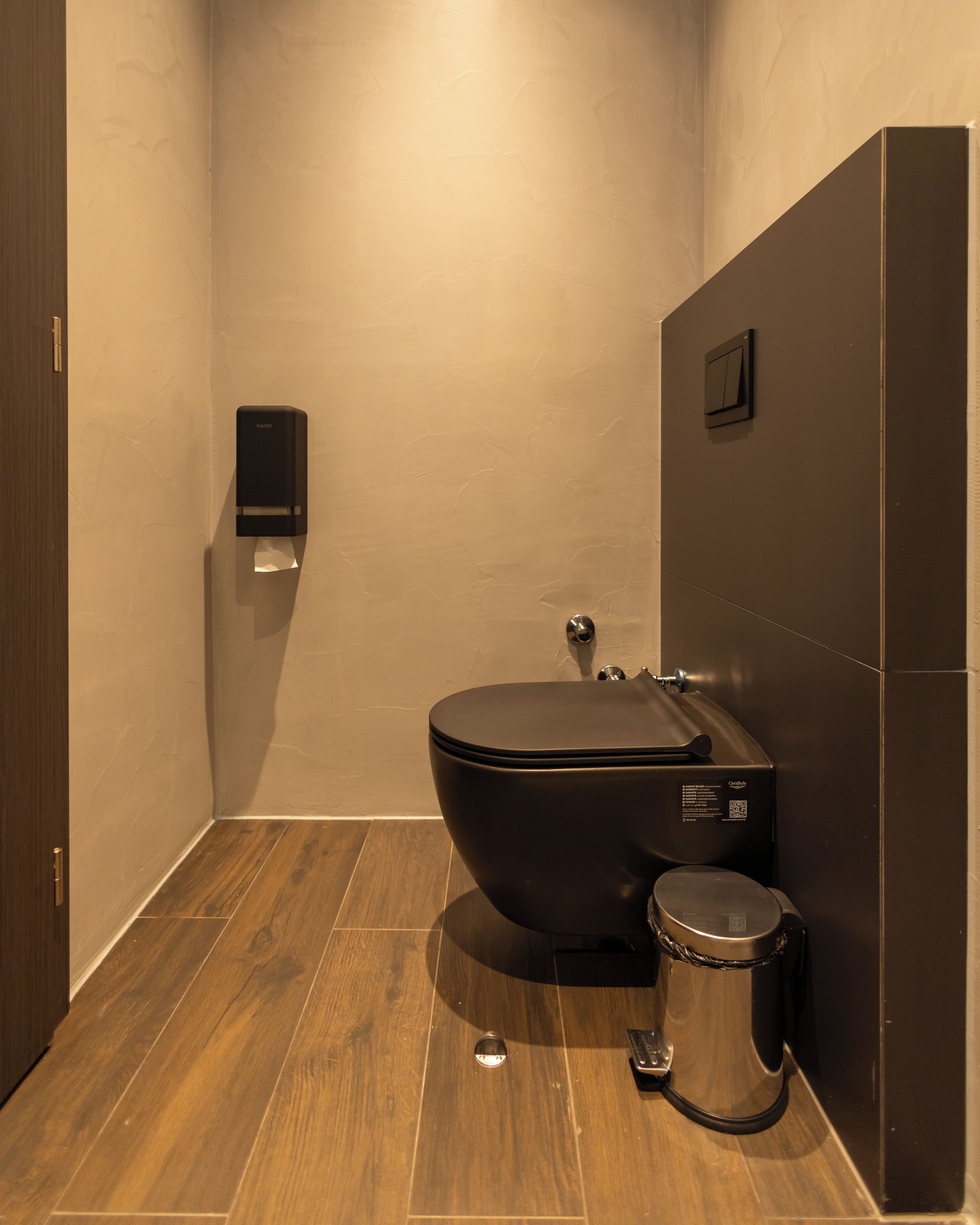 A modern bathroom with a toilet, bidet, and trash bin.