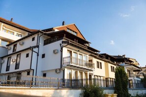 Un edificio de varios pisos con balcones y una entrada portonada.