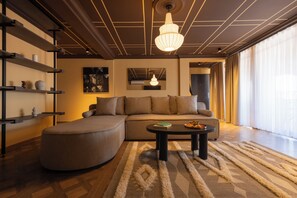 A modern living room with a sectional sofa, a round coffee table, and a large window with sheer curtains. - Agara Stays Prizren (Prizren)