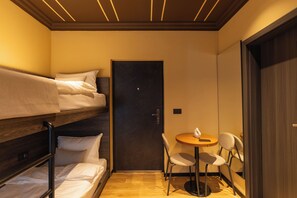 A compact room with a bunk bed, a small round table with a chair, and a door. - Agara Stays Prizren (Prizren)