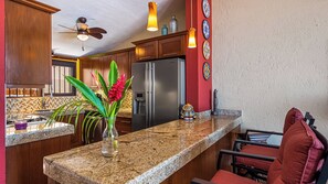 A kitchen with granite countertops, a stainless steel refrigerator, wooden cabinets, and a red accent wall. - SPECTACULAR views of Banderas Bay One Bedroom Condo in Centro (Puerto Vallarta)