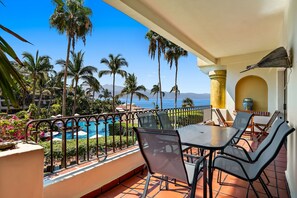 Una terraza con vista a la piscina, mobiliario exterior y palmeras.