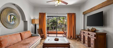 Un salon comprenant un canapé, une table basse, un téléviseur et un ventilateur de plafond.