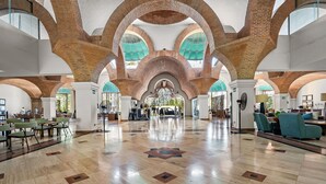 A spacious lobby with high brick arches, a polished floor, and seating areas. - Velas Resort Access Beachfront 3BR Condo (Puerto Vallarta)