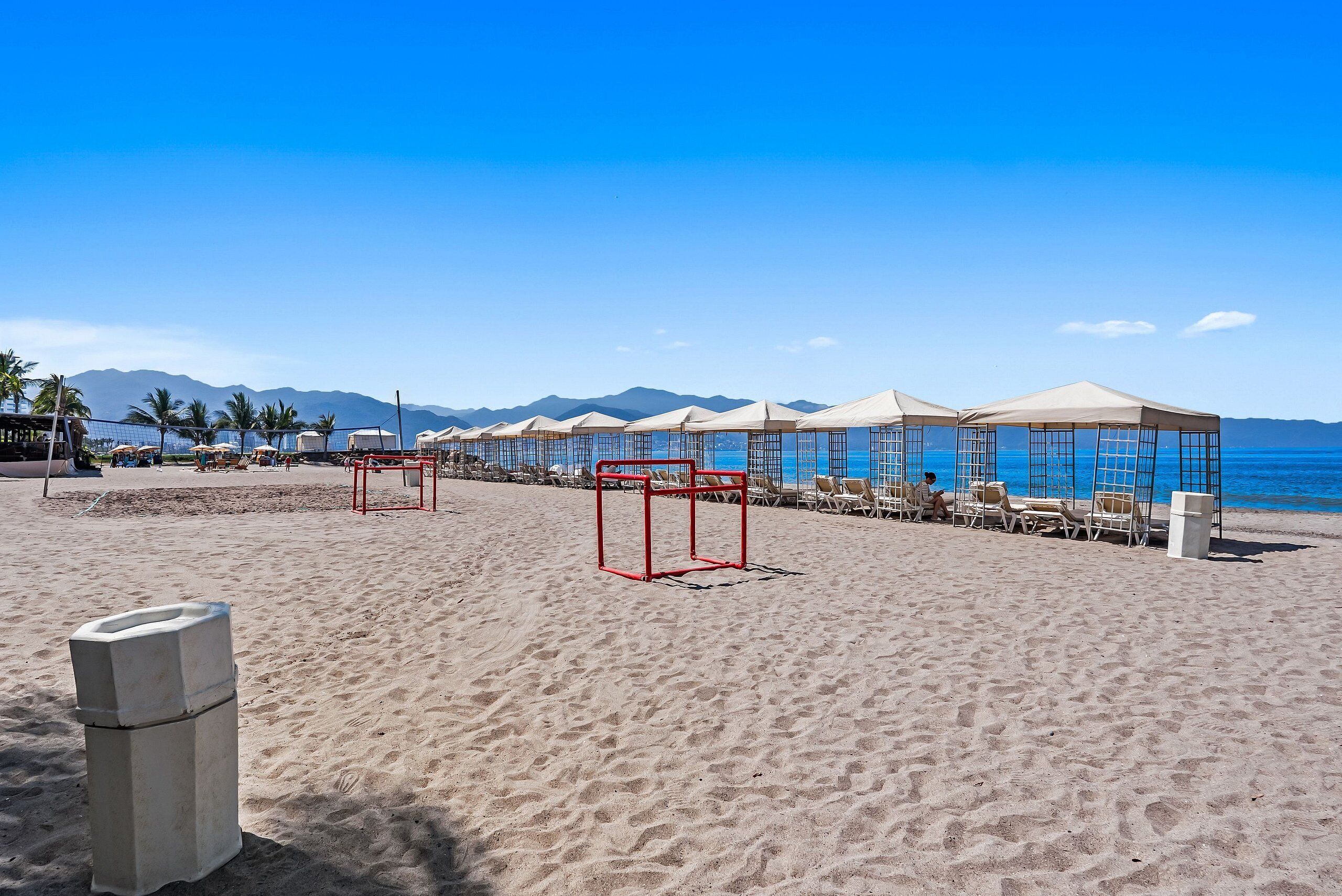 A beach with umbrellas, chairs, and a clear view of the sea and mountains.