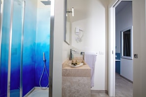 Un baño con cabina de ducha de vidrio, un lavabo con toalla y un espejo.