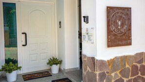 Fachada de hotel con una puerta blanca, una planta en maceta, un muro de piedra y una placa que indica servicios de Bed & Breakfast.
