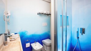 Un baño moderno con pared de degradado azul, cabina de ducha de vidrio, lavamanos y retrete.