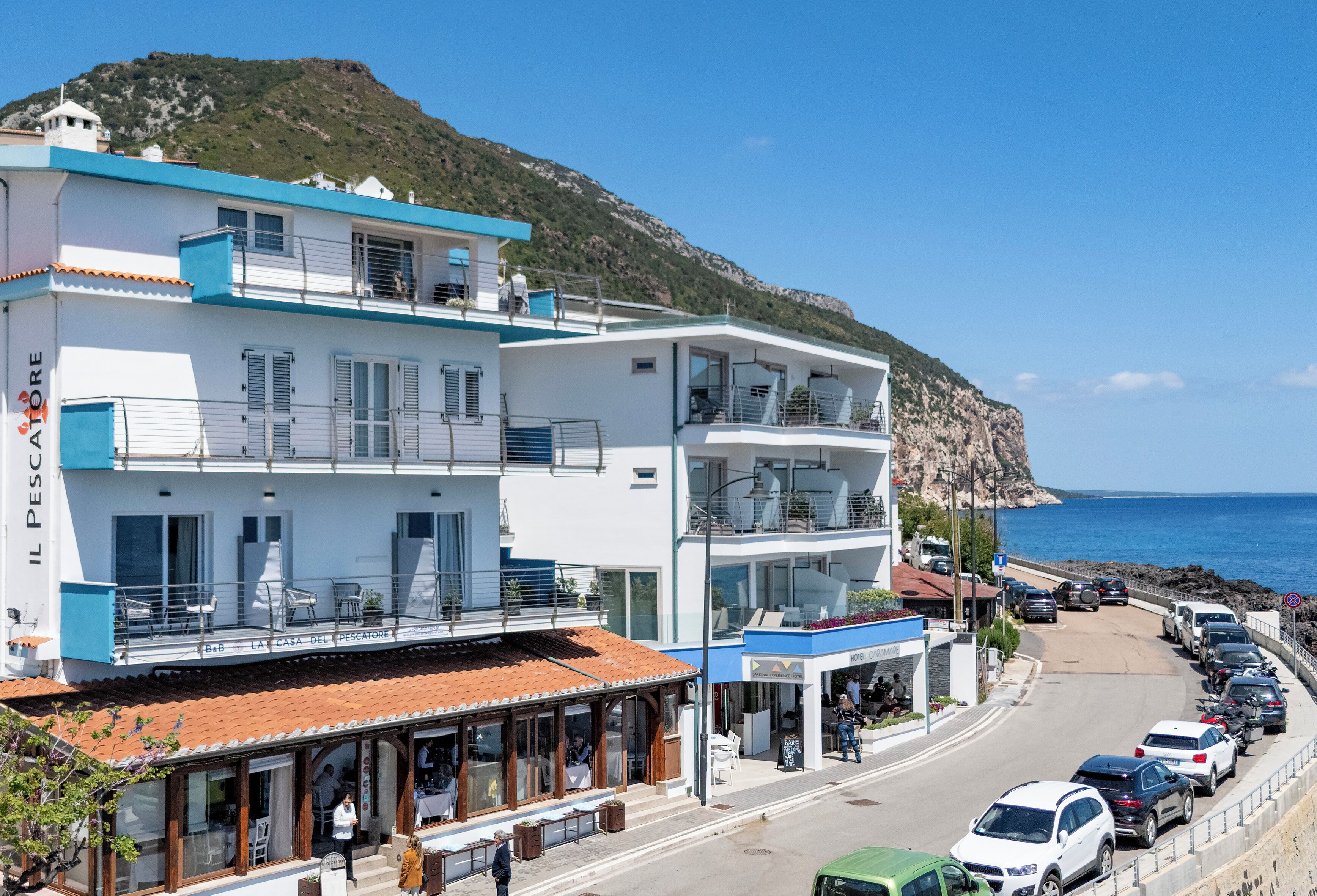 Un edificio costero con balcones, un restaurante y vistas al mar.