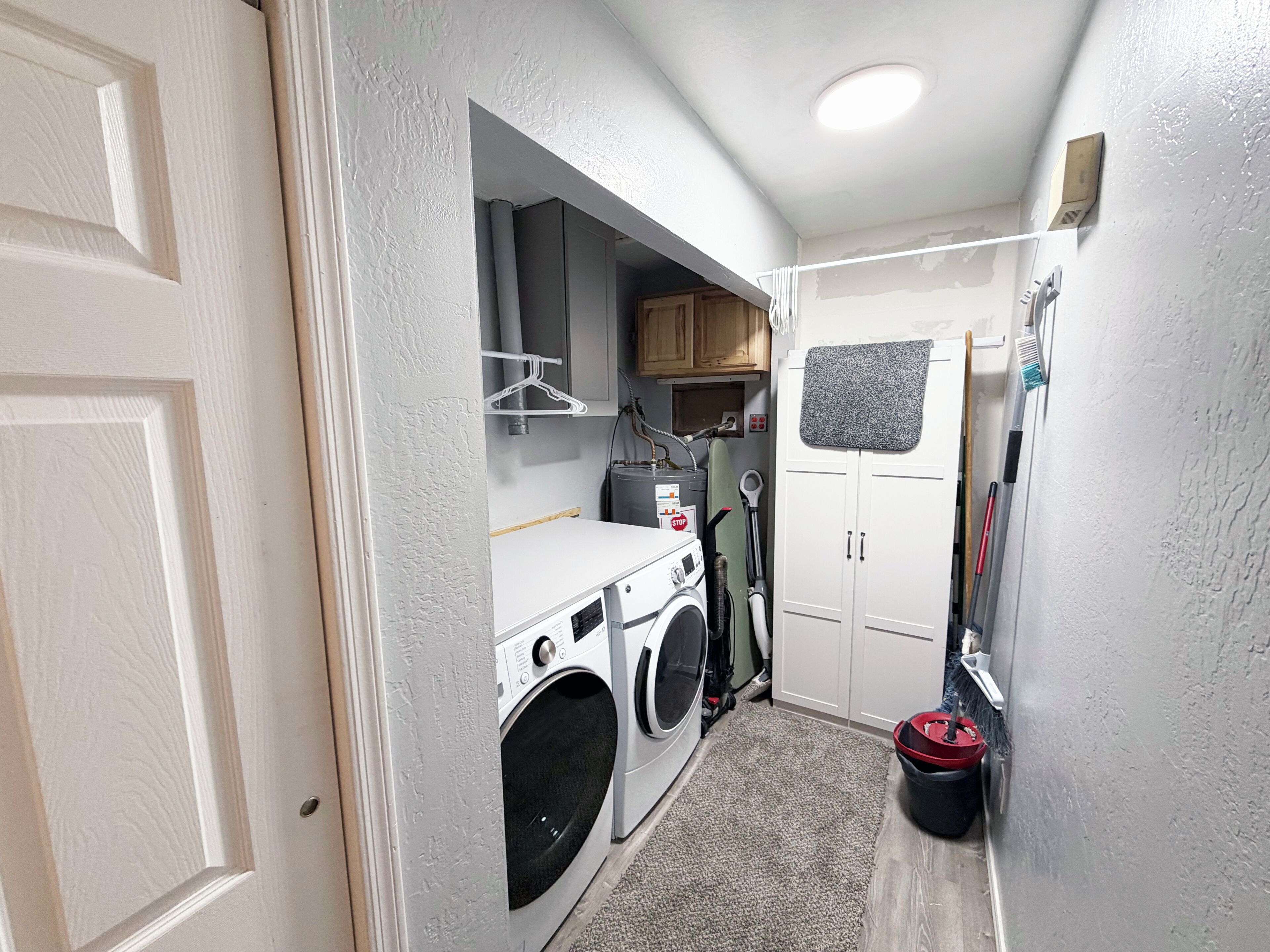 Une buanderie équipée d’un lave-linge, d’un étendoir et de placards.