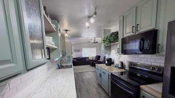 A modern kitchen with marble countertops, a built-in microwave, and a black stove. - Large Home, Sleeps 13, Hot Tub, Starlink, Air Conditioning (Eagar)