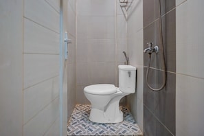 Eine kleine, geschlossene Duschkabine mit Toilette und Duschkopf.