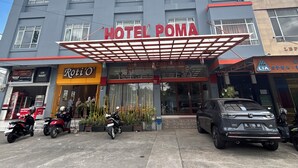 A hotel with a prominent entrance, multiple windows, and a parking area with motorcycles and a car. - Townhouse Oak near RSUD Dr. Zainoel Abi (Banda Aceh)