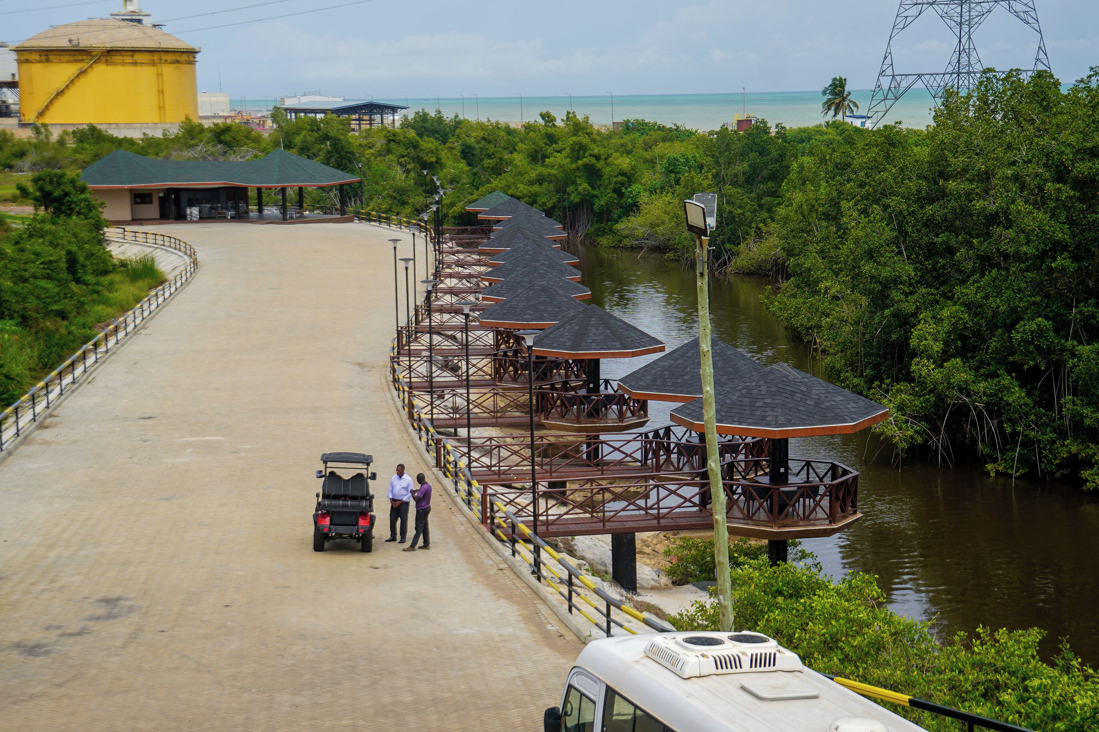 Un resort costero con un muelle largo, bungalows sobre el agua y un gran edificio amarillo.