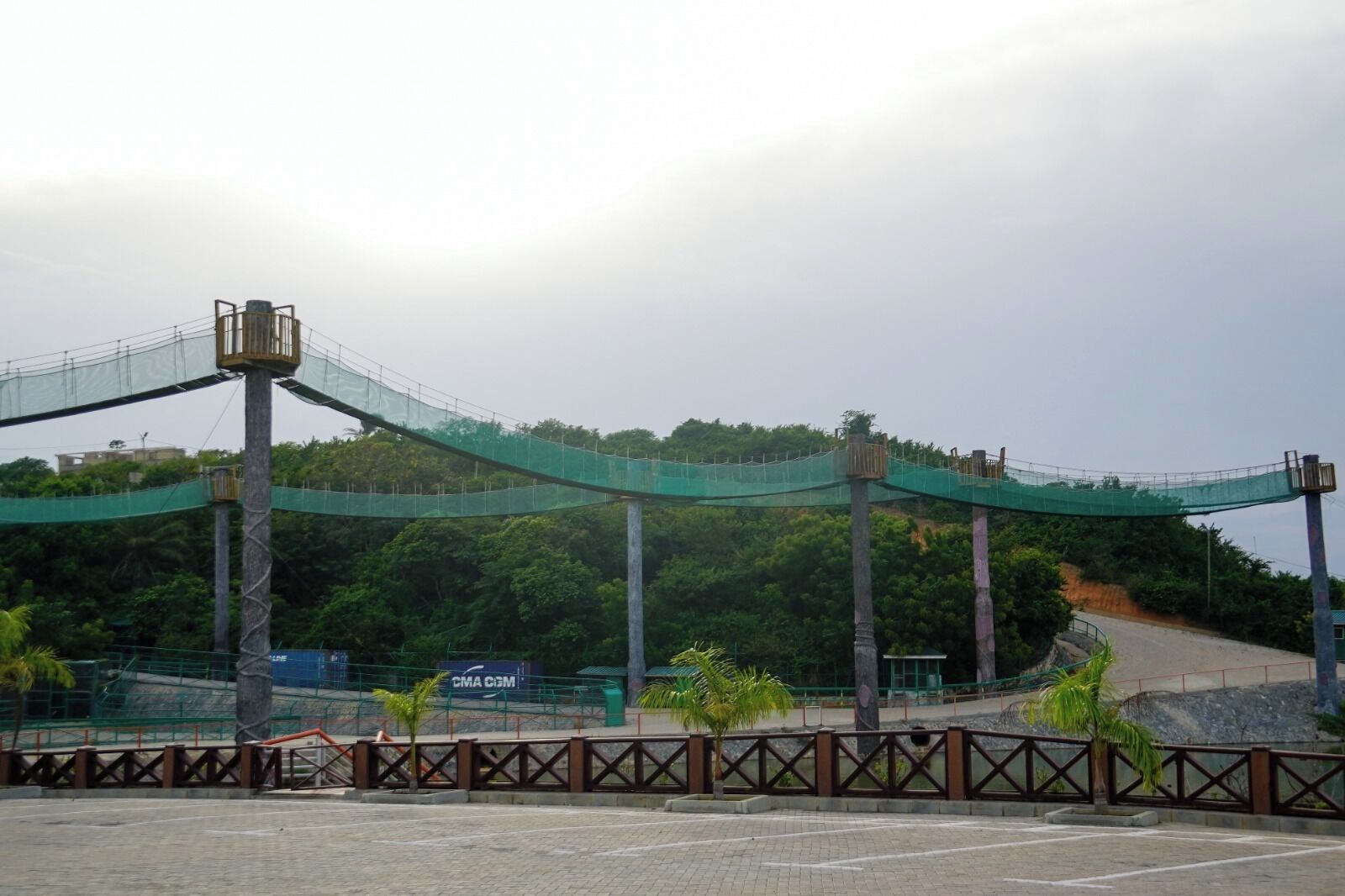 A pedestrian bridge with a netted walkway, a signboard, and a guardrail.