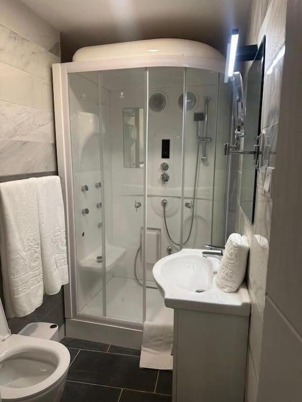 A modern bathroom with a glass-enclosed shower, a white sink, and a toilet. - THE GROVE ESSIPONG BEACH RESORT (Sekondi-Takoradi)