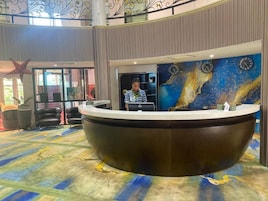 Un mostrador de recepción de diseño curvo, un mural con relojes y una decoración con estrellas.