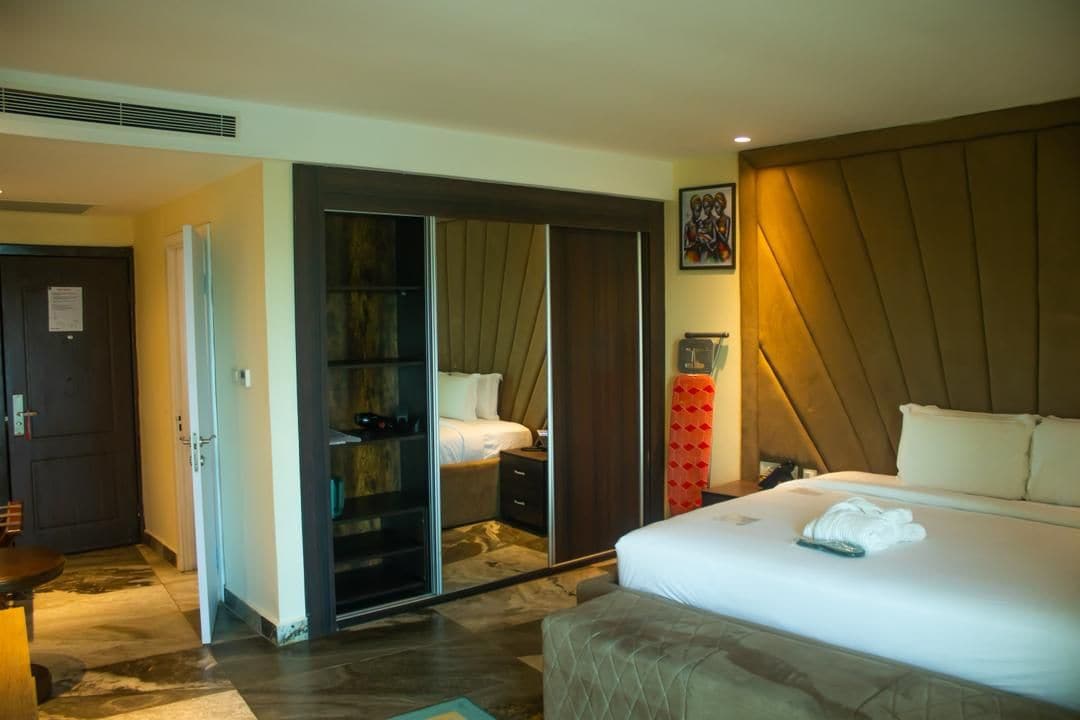 A hotel room with a bed, a wardrobe, a mirror, and a nightstand.