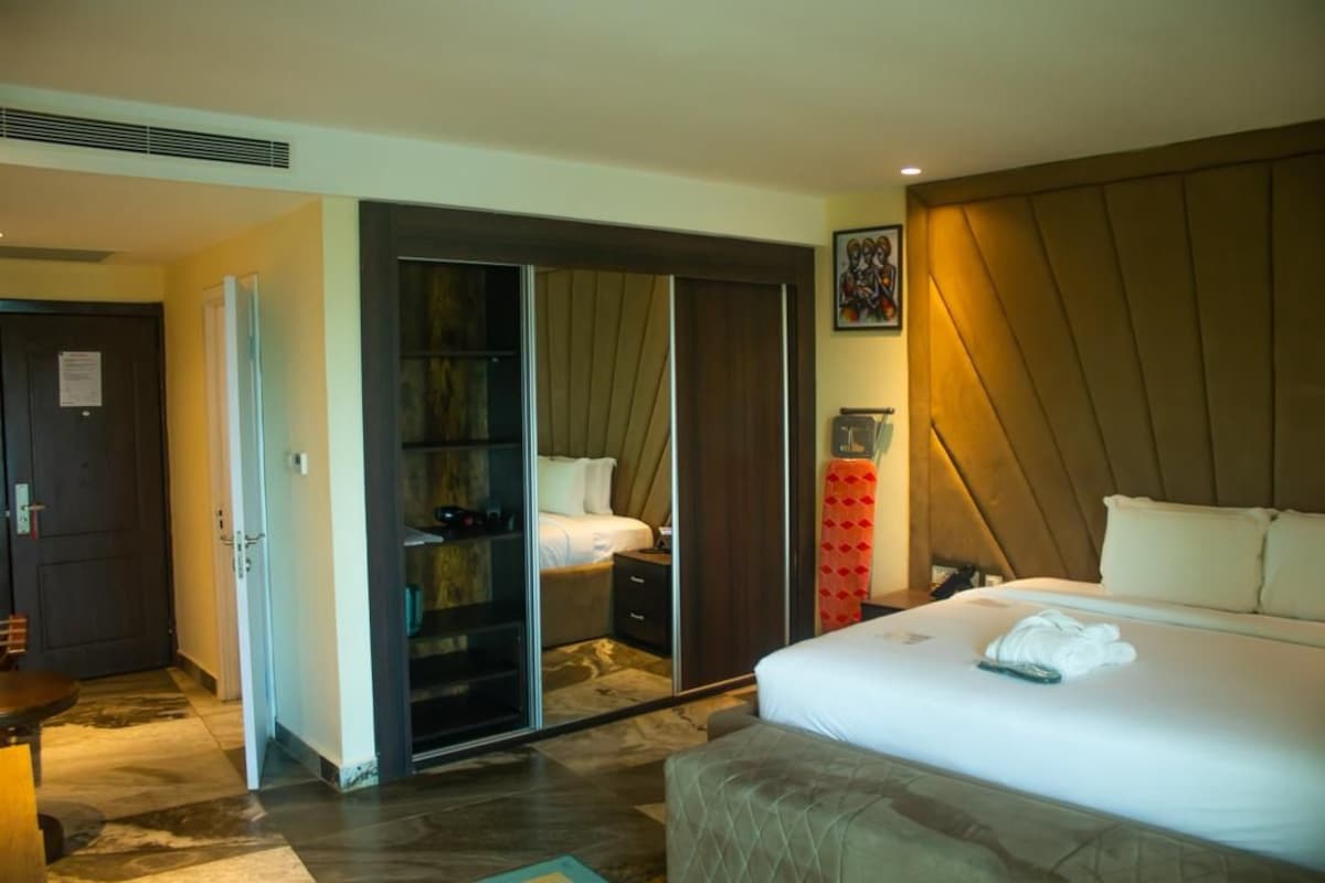A hotel room with a bed, a wardrobe, a mirror, and a nightstand.