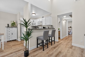 A modern kitchen with white cabinets, a microwave, and a bar area with two chairs. - Beautiful 2 Bedroom Condo 10 min from the Strip (Las Vegas)