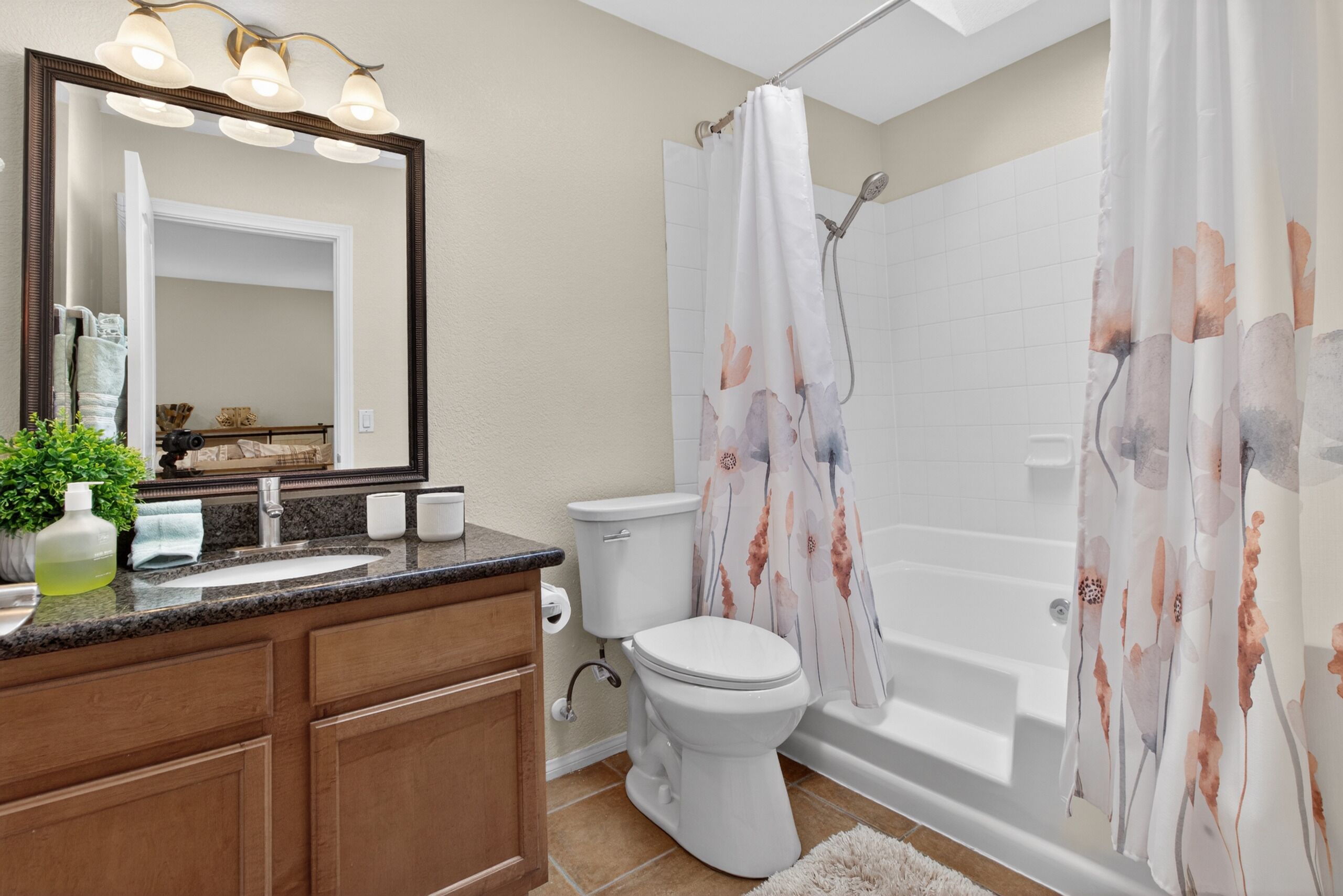A bathroom with a sink, mirror, toilet, and bathtub.