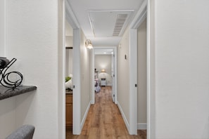 A hallway with wooden flooring, white walls, and a ceiling vent. - Beautiful 2 Bedroom Condo 10 min from the Strip (Las Vegas)