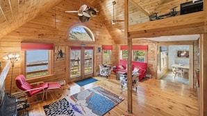 Ein Holzblock-Interieur mit Schlafzimmer im Zwischengeschoss, Essbereich und Blick ins Freie.