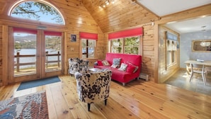 Eine Holzhütte mit roten Sofa, einem Sitze aus Rindsleder und einem Essbereich.