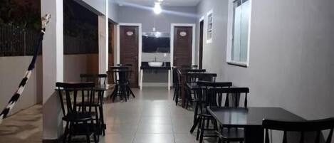 A corridor with multiple tables and chairs, a ceiling fan, and a window on the right.