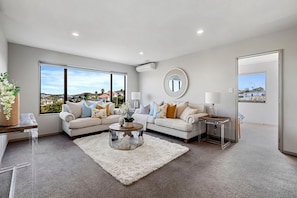 A spacious living room with two sofas, a coffee table, and a large window offering a view of the city. - Pinehill Extra-Large 8 Bedrooms House (North Shore)