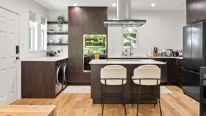 Una cocina moderna con una isla central, electrodomésticos integrados y un amplio ventanal.