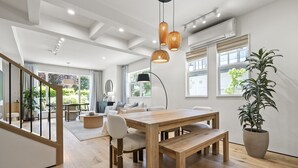 Un interior moderno con una mesa de comedor de madera, sillas, una planta en maceta y una escalera.