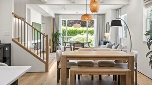 Un interior moderno con comedor, escalera y ventanas amplias.