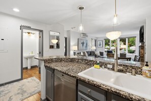 Eine moderne Küche mit Granit-Arbeitsflächen, Edelstahlgeräten und Pendelleuchten.