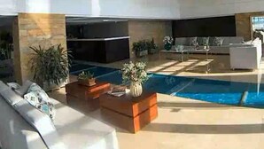 A spacious living area with a pool, modern furniture, and large pendant lights. - CRESPO OCEAN VIEW APT (Cartagena de Indias)