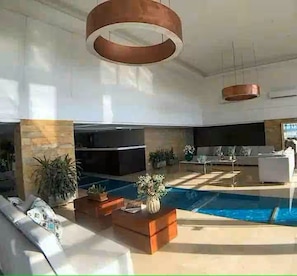 A spacious living area with a pool, modern furniture, and large pendant lights. - CRESPO OCEAN VIEW APT (Cartagena de Indias)