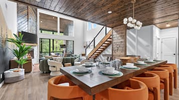 A modern interior with a dining area, wooden ceiling, and a staircase.