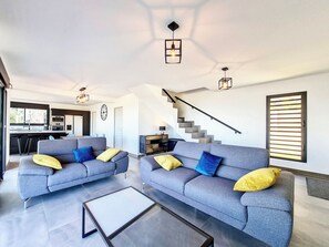 Un salon moderne avec deux canapés gris, une table basse et un escalier menant à un niveau supérieur.