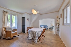 A dining area with a table, chairs, and a ceiling light fixture. - Maison Cosy - Jardin - Wifi (Trignac)